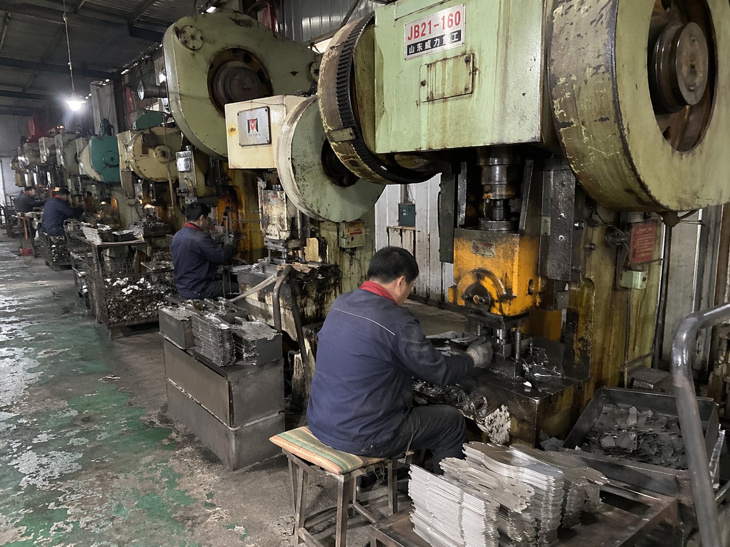 Workers handling knife part production on a pressing line